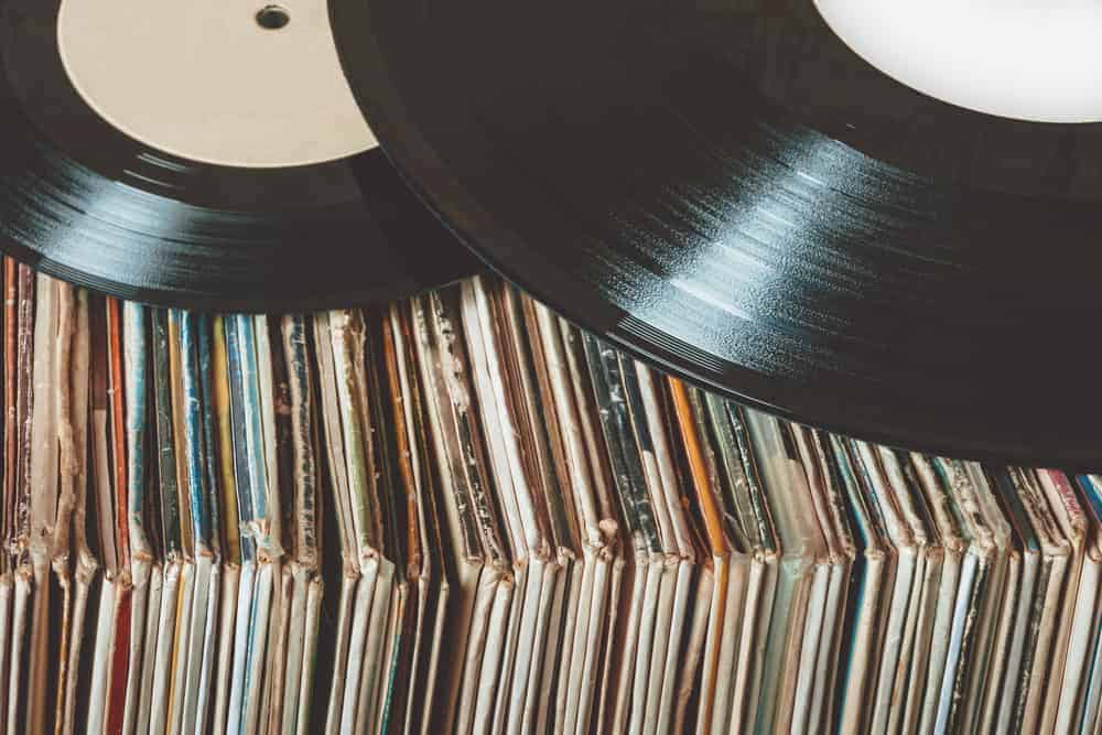 two vinyl records laying on many records in sleeve
