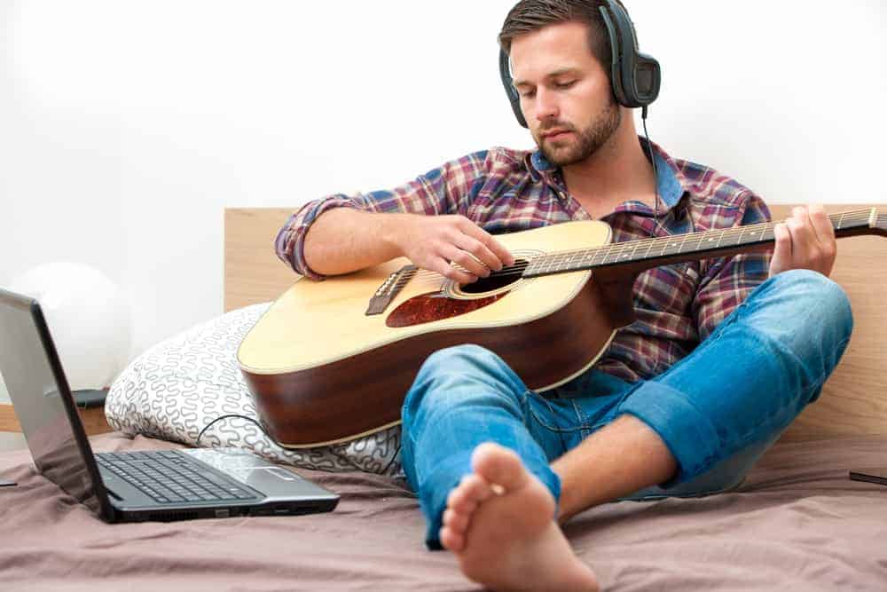 caucasian stay at home father playing a guitar with head phones