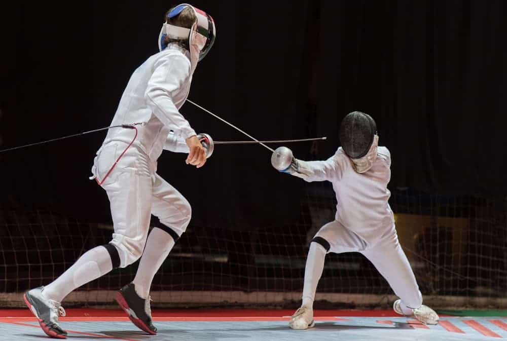 two people in white suits fencing with swords as one handed hobbies