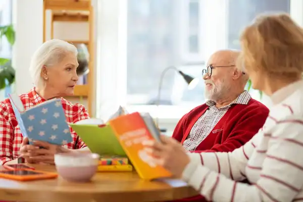 Elderly man and woman sitting together at a table, each reading their own book