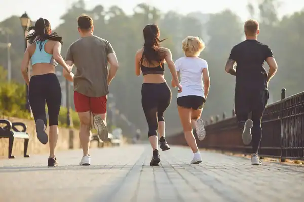 Five friends jogging together along a paved outdoor path in the morning light