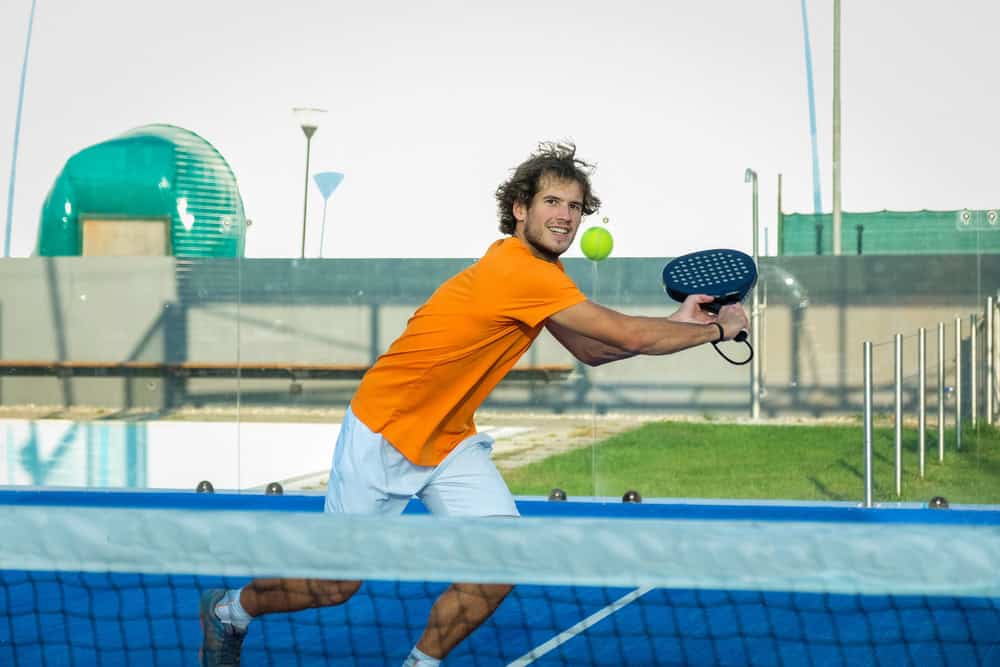 Padel player hitting a forehand shot on an outdoor court